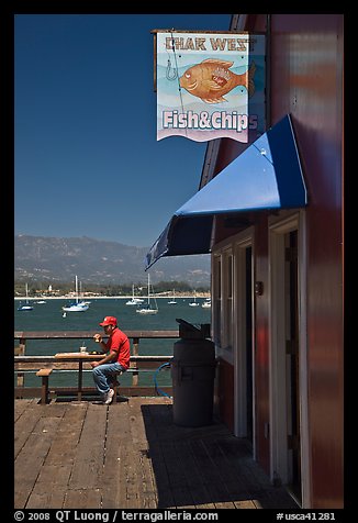 Man eating on wharf next to Fish and Chips restaurant. Santa Barbara, California, USA