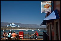 People eating with yachts and beach in background. Santa Barbara, California, USA