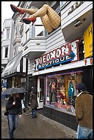 Woman passing with unbrella below giant legs. San Francisco, California, USA