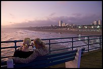 Two women sitting on bench at sunset , Santa Monica Pier. Santa Monica, Los Angeles, California, USA (color)