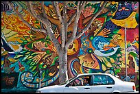 Man sitting in car, mural, and tree, Mission District. San Francisco, California, USA (color)