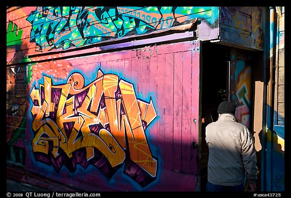 Man opening door of painted garage, Mission District. San Francisco, California, USA (color)