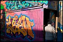 Man opening door of painted garage, Mission District. San Francisco, California, USA ( color)