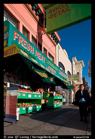 Woman walks past vegetable store, Mission Street, Mission District. San Francisco, California, USA