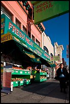 Woman walks past vegetable store, Mission Street, Mission District. San Francisco, California, USA