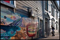 Mural and man entering house with grocery bags, Mission District. San Francisco, California, USA