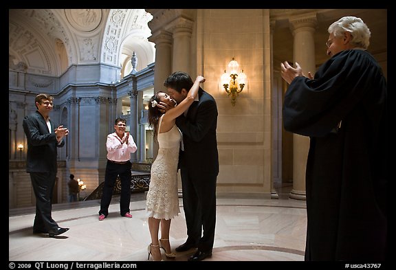 Just married couple kissing, witness and officiant applauding, City Hall. San Francisco, California, USA