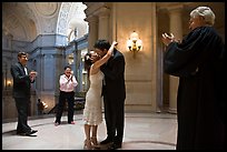 Just married couple kissing, witness and officiant applauding, City Hall. San Francisco, California, USA (color)