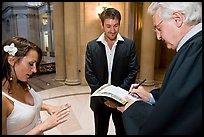 Officiant signing marriage papers as bride looks at ring on finger, City Hall. San Francisco, California, USA