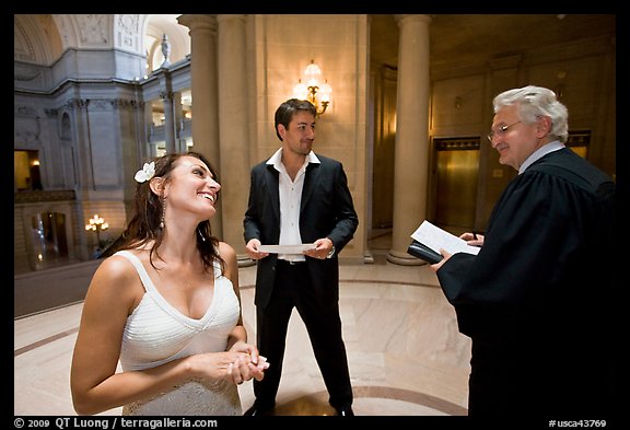 Bride and groom exchange smile with wedding official, City Hall. San Francisco, California, USA (color)