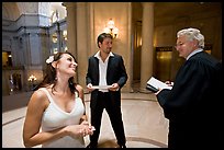 Bride and groom exchange smile with wedding official, City Hall. San Francisco, California, USA