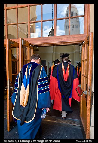 Professors in academic regalia walk into door with Hoover tower reflected. Stanford University, California, USA