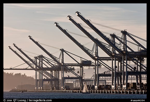 Giant cranes dwarf yacht Port of Oakland. Oakland, California, USA