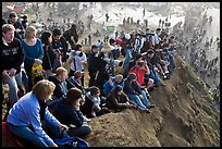 Spectators sitting on cliff to see mavericks contest. Half Moon Bay, California, USA