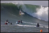 Surfer down huge wall of water observed from jet skis. Half Moon Bay, California, USA