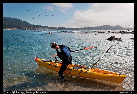 Man boards sea kayak, Carmel Bay. Carmel-by-the-Sea, California, USA