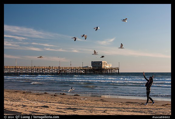 Woman and seagulls in front of Newport Pier. Newport Beach, Orange County, California, USA (color)