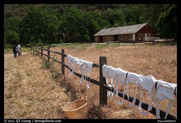 Laundry drying on fence, as elderly couple in period costume walks in distance, Fort Tejon. California, USA (color)