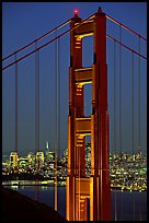 The city seen through the cables and pilars of the Golden Gate bridge, night. San Francisco, California, USA