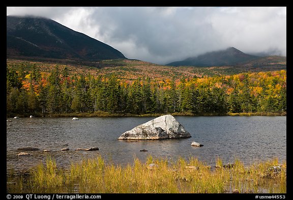 Boulder, pond, forest in autumn and mountains with clouds. Baxter State Park, Maine, USA (color)