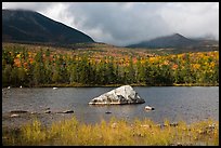 Boulder, pond, forest in autumn and mountains with clouds. Baxter State Park, Maine, USA (color)