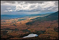 View with storm light and clouds over slopes covered with fall foliage. Baxter State Park, Maine, USA