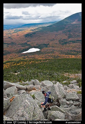 Hiker descends from summit amongst boulders above treeline. Baxter State Park, Maine, USA