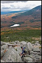 Hiker descends from summit amongst boulders above treeline. Baxter State Park, Maine, USA