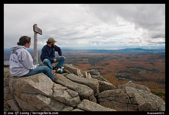 Hikers taking in view near sign marking summit of South Turner Mountain. Baxter State Park, Maine, USA