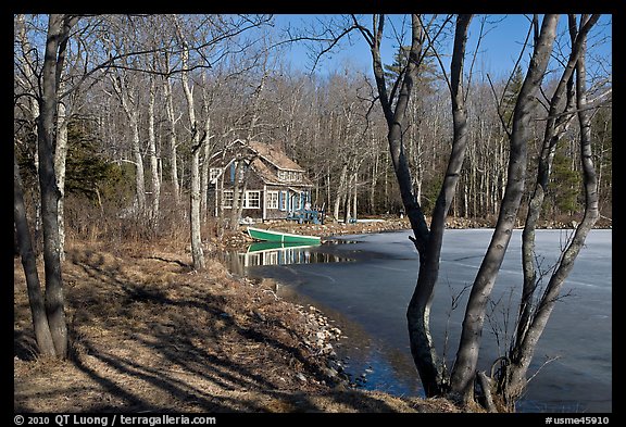 Lake, forest, and house in late winter. Maine, USA