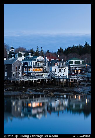 Houses with lights reflected in harbor. Stonington, Maine, USA