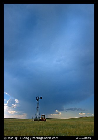 Windmill and tractor under a threatening stormy sky. North Dakota, USA