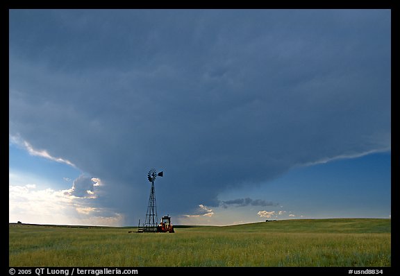 Windmill and tractor under a threatening stormy sky. North Dakota, USA