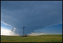 Windmill and tractor under a threatening stormy sky. North Dakota, USA