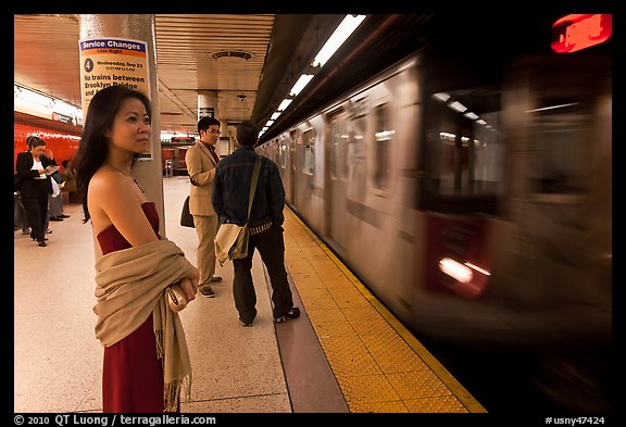 Young woman and arriving train on subway platform. NYC, New York, USA
