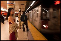 Young woman and arriving train on subway platform. NYC, New York, USA