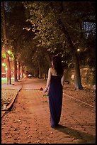 Woman in evening dress with rose on alley bordering Central Park at night. NYC, New York, USA ( color)