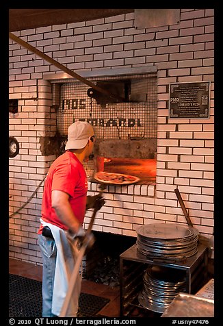 Man loading pizza into oven, Lombardi pizzeria. NYC, New York, USA (color)