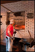 Man loading pizza into oven, Lombardi pizzeria. NYC, New York, USA (color)