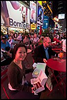 Woman with cupcakes sitting on Times Squares at night. NYC, New York, USA (color)