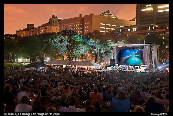 Outdoor musical performance at night with QTL photo as screen backdrop, Central Park. NYC, New York, USA