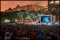 Outdoor musical performance at night with QTL photo as screen backdrop, Central Park. NYC, New York, USA