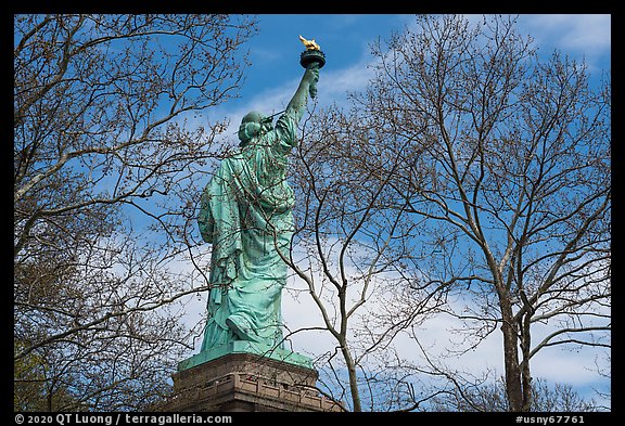 Statue of Liberty from the back between trees, Statue of Liberty National Monument. NYC, New York, USA (color)