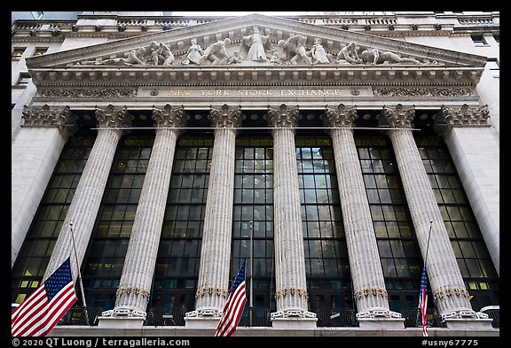 Looking up New York Stock Exchange with flags at half-mast. NYC, New York, USA