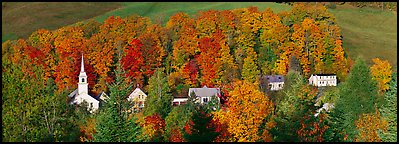 White-steppled church and houses amongst trees in fall foliage. Vermont, New England, USA