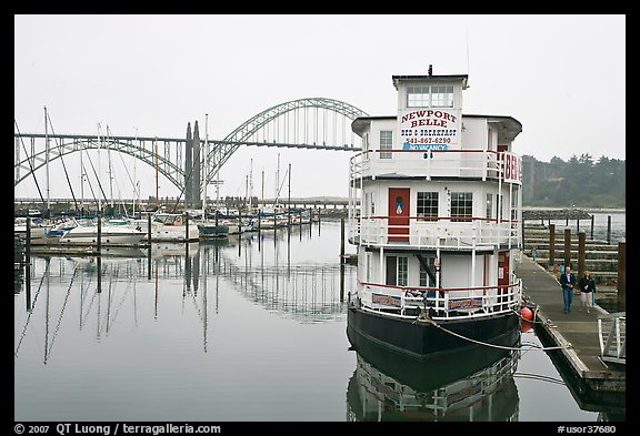 Couple walking on deck next to floating Bed and Breakfast. Newport, Oregon, USA (color)