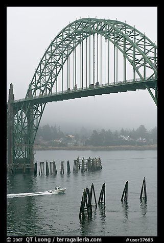 Small boat heading towards ocean under Yaquina Bay Bridge. Newport, Oregon, USA