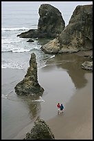 Women walking on beach among rock needles. Bandon, Oregon, USA