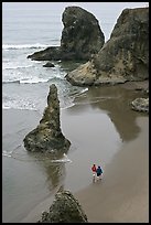 Women walking on beach among rock needles. Bandon, Oregon, USA (color)