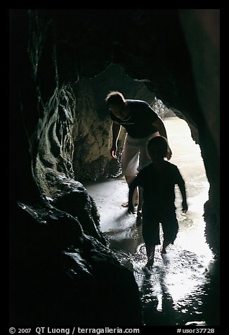 Boy and man exploring sea cave. Bandon, Oregon, USA (color)